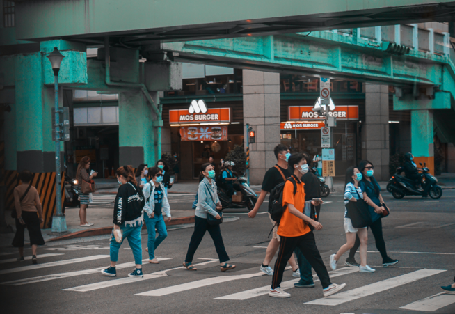 group of citizens wearing surgical masks in Taipei crossing a sidewalk under a pedestrian bridge